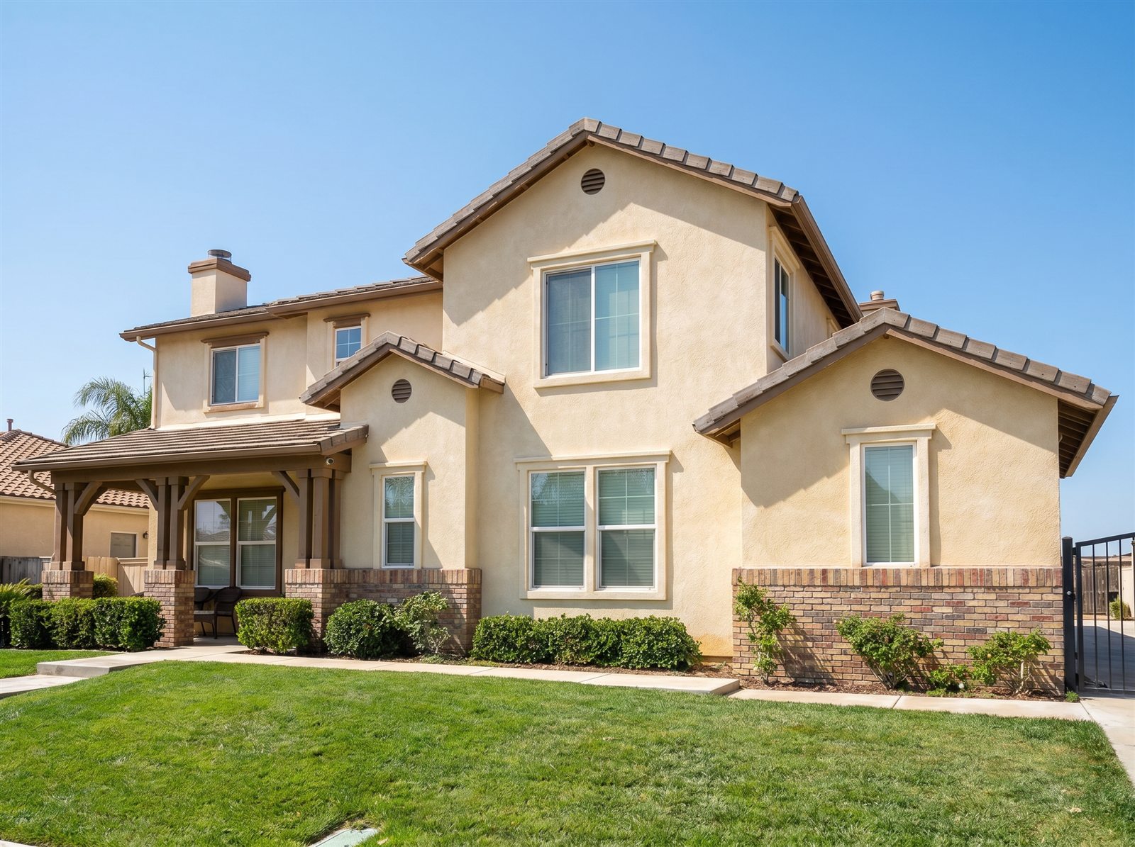 Completed cream Spanish-style stucco home with brick wainscot